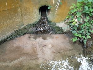 A polluted drain spills into a river