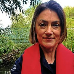 Sara Marshall, Digital Marketing and Fundraising Senior Officer at SERT, standing in front of a river with a red life jacket on.